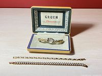 Vintage Gruen watch in original box with two vintage tennis bracelets lying in front.