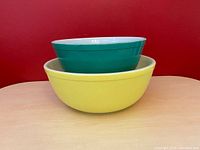 Two vintage Pyrex mixing bowls stacked - green smaller bowl inside large yellow bowl