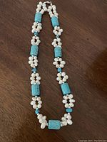 Full view of 18 inch necklace showing white freshwater pearls and bright blue turquoise beads arranged in clusters and spaced along the necklace