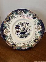 Front view of the round plate showing floral handpainted design and border