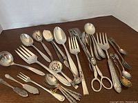Full view of all assorted silver tone serving pieces arranged on brown wooden surface.