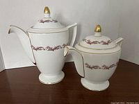 Photo showing Minton Laurentian white porcelain coffee pot and teapot with maroon scroll pattern and gold details, both with lids.