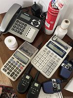 Panasonic phone, Sharp adding machines, walkie-talkies, and paper rolls on desk surface