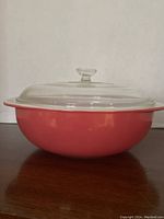 Side view of the flamingo pink casserole dish with clear glass lid showing dish shape and color.