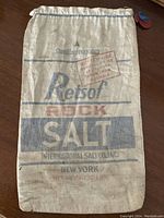 Front view of the vintage Retsof Rock Salt sack showing printed blue and red text with drawstring top and round tag.
