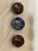 Three early Bennington pottery marbles arranged on white cloth showing wear and glaze variations.