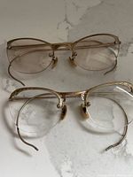Two pairs of 12k gold-filled vintage eyeglasses with bifocal lenses placed flat, showing front view and frame design.