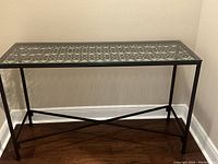 Photo of console table with forged iron frame and glass top and lower shelf, showing elegant design and sturdy construction.