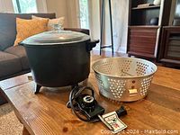 Electric deep fryer showing pot, glass lid, perforated metal basket, and temperature control dial with attached cord.