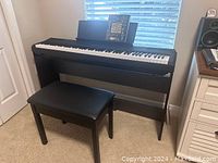 Yamaha digital piano P-105 on black stand with bench