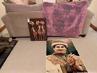 View showing batik wall hanging and carved wooden figure cloth art leaning against sofa, portrait mat on the floor