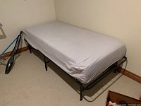 Single bed with Lucid memory foam mattress on black metal frame against wall, room corner showing.