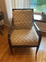 Front view of chair with cushions showing beige fabric with white geometric pattern on seat and backrest, dark wood frame.