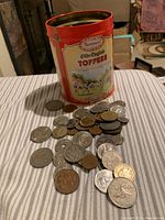 Coins placed beside and inside a red Olde English Toffees tin, showing quantity and variety of coins available in the lot.