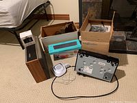 Wide view of entire lot including Philips 8 track player, Logitech keyboard box, HoMedics device, Cisco Nextbox, Majestic projector box.