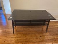 Front view of the wooden extending console table with folded leaves on top and visible lower shelves.