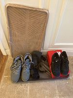 Full lot showing black Puma sneakers on red box, gray Harlan sneakers, two brown plastic boot trays behind shoes.
