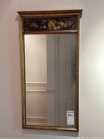 Full front view of mirror showing gilt wood frame and painted panel