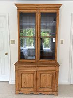 Front view of two-piece pine hutch cabinet showing upper glass doors and lower storage cabinet