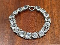 Close-up of the bracelet showing round clear paste stones and sterling silver links with spring ring clasp.