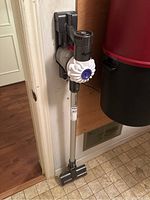 Vacuum mounted on wall plate with silver wand and floor head visible