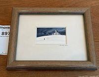 Full front view of framed painting with mat on wooden surface