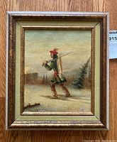 Frontal view of framed oil painting depicting a snowshoer carrying a fish through a winter landscape
