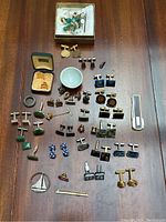Overall layout of cufflinks, studs, tie clips, pins and ring on table