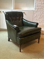 Angled front view of green vinyl armchair in room