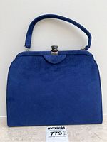 Front view of vintage royal blue suede handbag with flap top and silver-tone clasp.