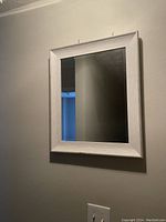 Front view of rectangular wall mirror showing silver and white textured frame and reflective surface.
