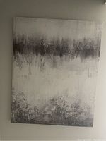 Full view of large abstract wall art piece leaning against a wall, showing charcoal gray, white and light gray blended shades.