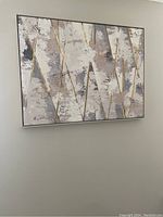 Wall art hung on a wall showing gold, cream, and charcoal grey triangular shapes with an abstract textured pattern in a rectangular frame.
