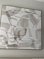 Front view of square wall art with abstract neutral color shapes and simple frame.