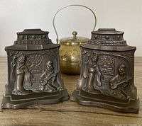 Front view of the pair of bronze Geisha bookends and the brass teapot displayed behind them.