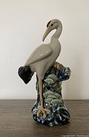 Front view of the porcelain crane vase showing the full bird figure standing on one leg atop detailed blue and green majolica base.