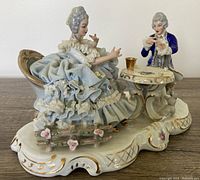 Front view of figurine couple playing cards at table on decorative base