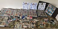 Photo showing several open binders filled with hockey cards along with loose hockey and baseball cards spread on a table, NHL autographed sheets in background.