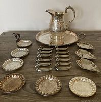 Photo of entire lot showing large engraved water jug on round tray, set of 4 coasters with greyhound holder, 12 cutting tool rests, and 4 swan ashtrays arranged on wooden surface.