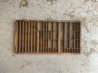 Top-down view showing compartments of the wooden typeset drawer on a concrete floor.
