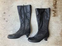 Side by side view of black leather boots with kitten heel and lace detail on upper shaft