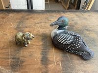 Photo showing wooden loon and marble elephant sculpture on a wooden table.