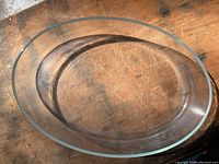 Clear oval glass Pyrex pan on wooden surface showing shape and size.
