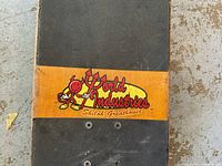 Close-up of the skateboard deck showing the World Industries logo and Shiloh Greathouse text on an orange strip under grip tape.