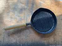Top view of the small cast iron grill pan showing the ridged grilling surface and wooden handle.