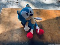 Front angle of Sonic the Hedgehog plush toy on wooden surface