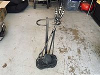 Full view of the wrought iron fireplace tool set with all tools hanging on the holder, showing the base and the tools' handles