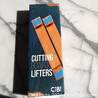 Photo of two bamboo cutting board lifters with blue non-slip pads in original packaging on a marble surface.