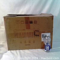Closed original cardboard box of the Fabuletta air fryer oven next to a water bottle for size reference.