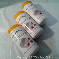 Three white cylindrical containers of PowerPunch sanitizing wipes with yellow lids, placed on a white surface.